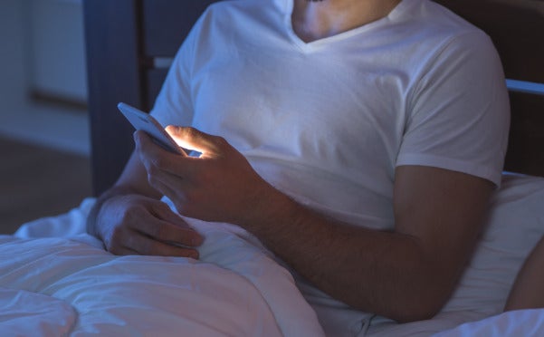 homme sur son téléphone au lit
