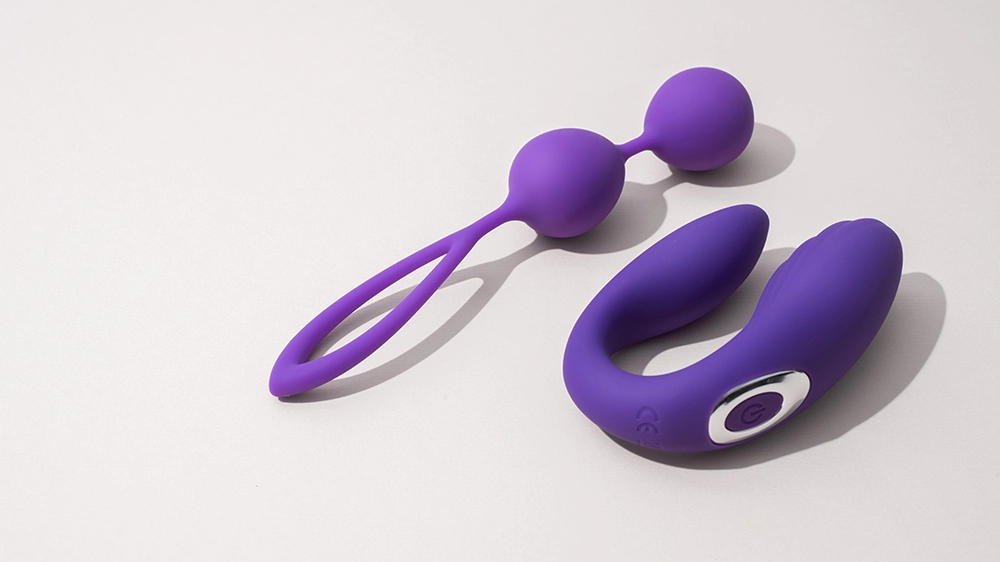  Deux sextoys en silicone violet sur fond clair, adapt&eacute;s pour d&eacute;buter : boules de geisha et stimulateur de couple.