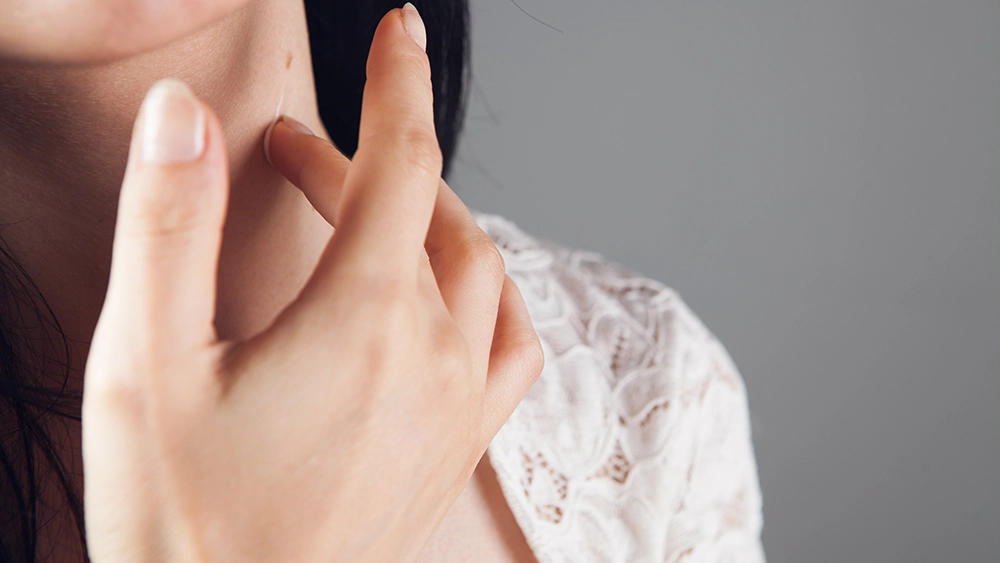 Main touchant délicatement la peau du cou pour illustrer les zones érogènes et la stimulation en douceur.